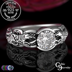 May include: A sterling silver ring with a large, clear gemstone at the center. The band features intricate Celtic knotwork and wolf designs. The ring is nickel-free and hand-crafted in the USA.