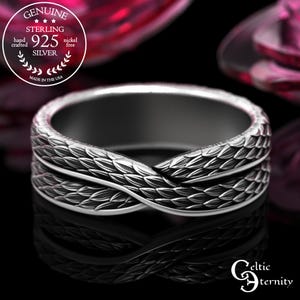 May include: A sterling silver ring with a textured, interwoven design. The ring features a repeating pattern of leaf-like shapes. The ring is marked with "925 SILVER" and "MADE IN THE USA". The ring is nickel free.