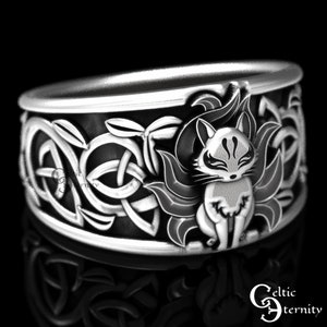 Pu&ograve; includere: Un anello d'argento con un designo a nodo celtico e un'immagine dettagliata di una volpe a nove code. La volpe &egrave; in piedi con la coda avvolta attorno al suo corpo. L'anello &egrave; un pezzo di dichiarazione con dettagli intricati.