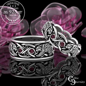 Puede incluir: Dos anillos celtas de nudo de plata de ley con piedras preciosas rojas. Los anillos presentan un diseño de nudos entrelazados y osos. El texto "Genuine Sterling 925 Silver" y "Made in the USA" es visible en la imagen.