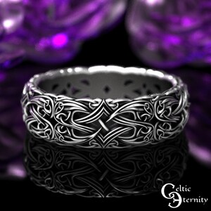 May include: A silver Celtic knot ring with an intricate design. The ring is made of a thick band with a detailed pattern of interwoven knots.