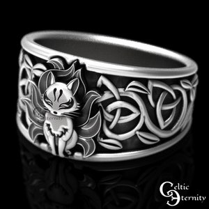 Pu&ograve; includere: Un anello d'argento con un designo a nodo celtico e un'immagine dettagliata di una volpe bianca con segni rossi. L'anello &egrave; posto su uno sfondo nero.