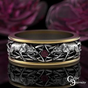 May include: A silver ring with a gold band featuring detailed wolf and pentagram designs. The ring has a central ruby-colored stone and the words "Celtic Eternity" are visible.