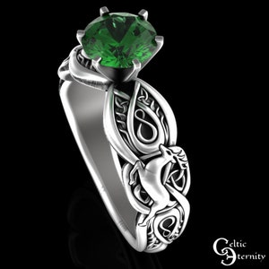 May include: A silver Celtic knot ring with a green gemstone and a detailed design of a deer. The ring is a symbol of eternity and love.