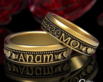 May include: Two gold wedding bands with Celtic knot designs. The top band has the word "MO" engraved on it, while the bottom band has the word "ANAM" engraved on it.