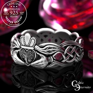May include: A sterling silver ring with a Celtic design. The ring features a crown, a heart with a tree, and knotwork. The ring is nickel-free and hand-crafted in the USA. The ring has red accents.
