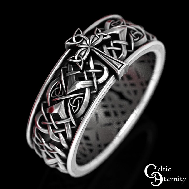May include: Silver Celtic knot ring with a cross design. The ring is intricately detailed and features a Celtic knot pattern.
