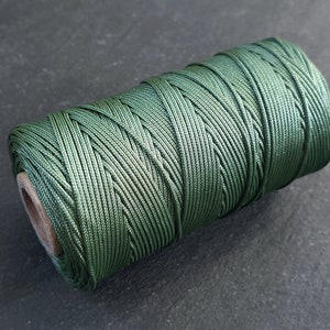 May include: A spool of dark green waxed cord.