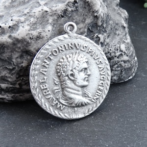 May include: Silver pendant featuring a Roman emperor bust with the inscription "IMP ANTONINVS PIVS AVG" around the edge.