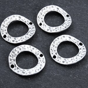 Può includere: Quattro anelli in metallo color argento con una texture martellata. Ogni anello ha due fori per attaccare i ritrovamenti di gioielleria.