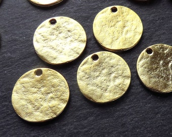 Puede incluir: Un conjunto de ocho círculos de metal de color dorado con una superficie texturizada y un pequeño agujero en el centro. Los círculos están dispuestos de forma aleatoria sobre una superficie negra.