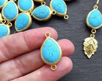May include: A collection of turquoise blue gemstone teardrop pendants with gold-tone metal settings. The pendants have a smooth, polished finish and are perfect for jewelry making.