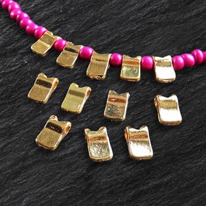 May include: Gold-colored metal bead caps for jewelry making. The caps have a slightly curved shape and a smooth finish. There are 10 caps in total.