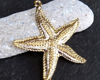 May include: Gold-coloured metal starfish charm pendant. The starfish has a detailed, textured surface.