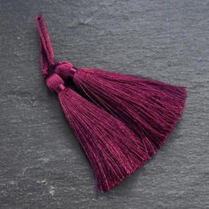 May include: Two burgundy tassels with a long, thin cord.