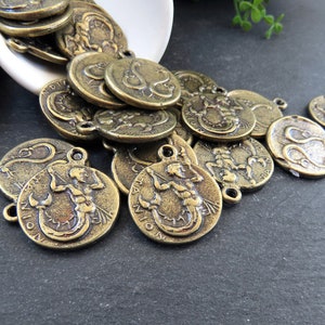 May include: A pile of antique gold-toned metal charms featuring the zodiac sign Scorpio. The charms are round and have a raised design of a scorpion.