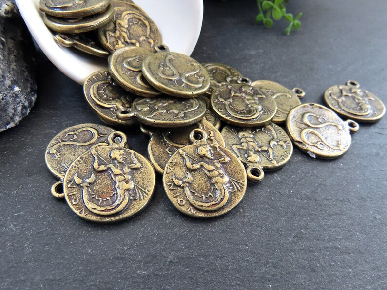 May include: A pile of antique gold-toned metal charms featuring the zodiac sign Scorpio. The charms are round and have a raised design of a scorpion.