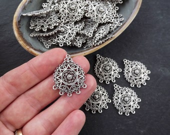 May include: Silver filigree pendant charms with a detailed mandala design. The charms have three loops at the top for attaching to jewelry.