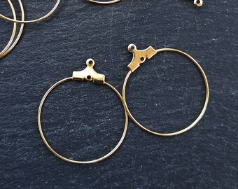 May include: Two gold hoop earrings with a clasp closure. The hoops are round and have a smooth finish.