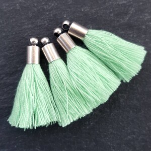 May include: Four light green tassel charms with silver metal tops. The tassels are made of soft, fluffy yarn.