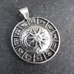 May include: Silver pendant featuring a circular design with the zodiac symbols and a sun and moon graphic.