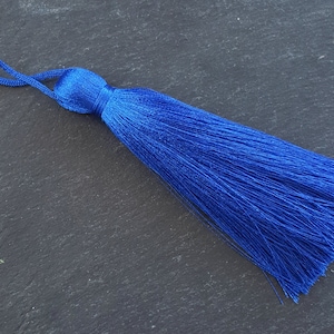 Puede incluir: Un borla azul brillante con un lazo para colgar. La borla está hecha de fibras suaves y sedosas y mide aproximadamente 5 cm de largo.