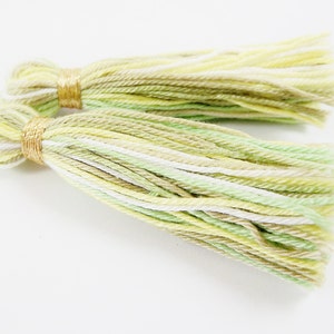 May include: Two green, white, and beige yarn tassels with gold trim.