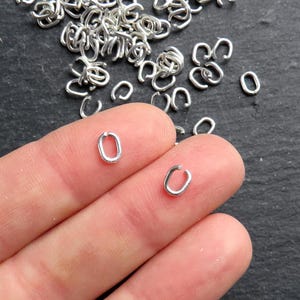 May include: Silver jump rings, oval shaped, for jewelry making. The rings are small and delicate, perfect for adding a touch of elegance to your designs.