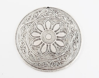 May include: A silver pendant with a detailed floral design. The pendant features a central flower with eight petals and a smaller circle in the center. The flower is surrounded by a decorative border.