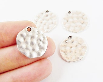 Peut inclure: Quatre breloques en métal argenté avec une texture martelée et un trou pour les attacher à des bijoux ou d'autres objets artisanaux.