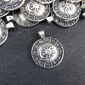 May include: Silver pendant featuring a sun and moon design with zodiac symbols around the edge.