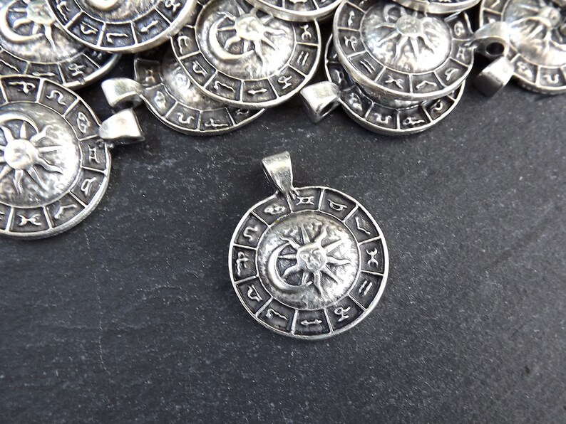 May include: Silver pendant featuring a sun and moon design with zodiac symbols around the edge.