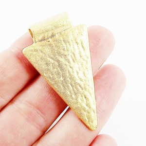 May include: Gold-toned metal arrowhead pendant with a textured surface.