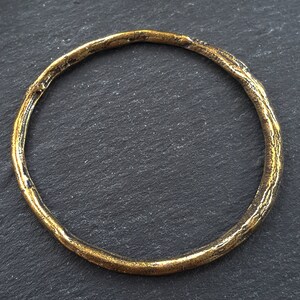 Puede incluir: Un brazalete de metal dorado con una superficie texturizada.