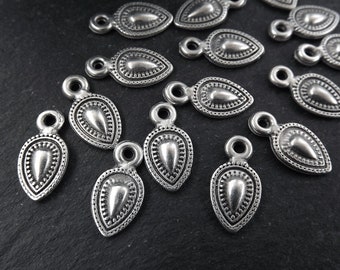 May include: A group of silver teardrop-shaped charms with a decorative design. Each charm has a small loop at the top for attaching to jewelry or other crafts.