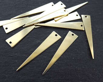 May include: A collection of brass-colored, triangular metal pieces with a hole at the top. The pieces are flat and elongated, with a pointed end. The metal has a shiny, reflective surface. These components are likely for jewelry making or other craft projects.