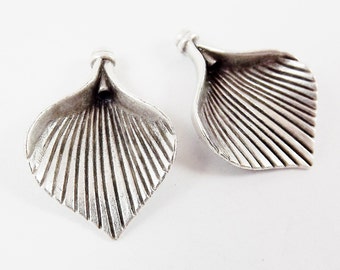 May include: Two silver metal leaf-shaped charms with a textured surface. The charms have a hole at the top for attaching to jewelry or other crafts.