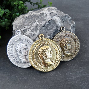 May include: Three antique-style coin pendants with Roman emperor busts and Latin inscriptions. The pendants are silver, gold, and bronze.