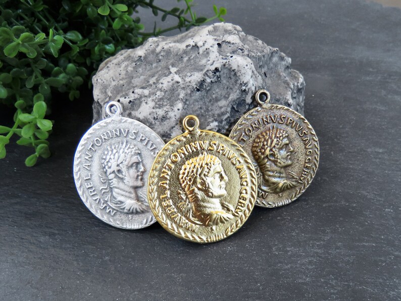 May include: Three antique-style coin pendants with Roman emperor busts and Latin inscriptions. The pendants are silver, gold, and bronze.