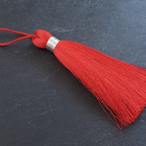 May include: A bright red tassel with a silver ring at the top and a red cord loop.