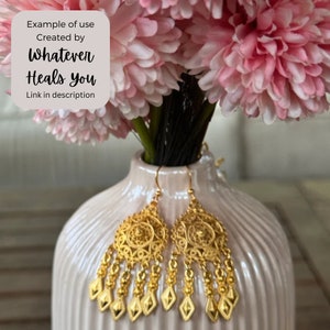 May include: A pair of gold dangle earrings with intricate filigree designs. The earrings feature a round, openwork top with a dangling chain of small, round beads and diamond-shaped charms.