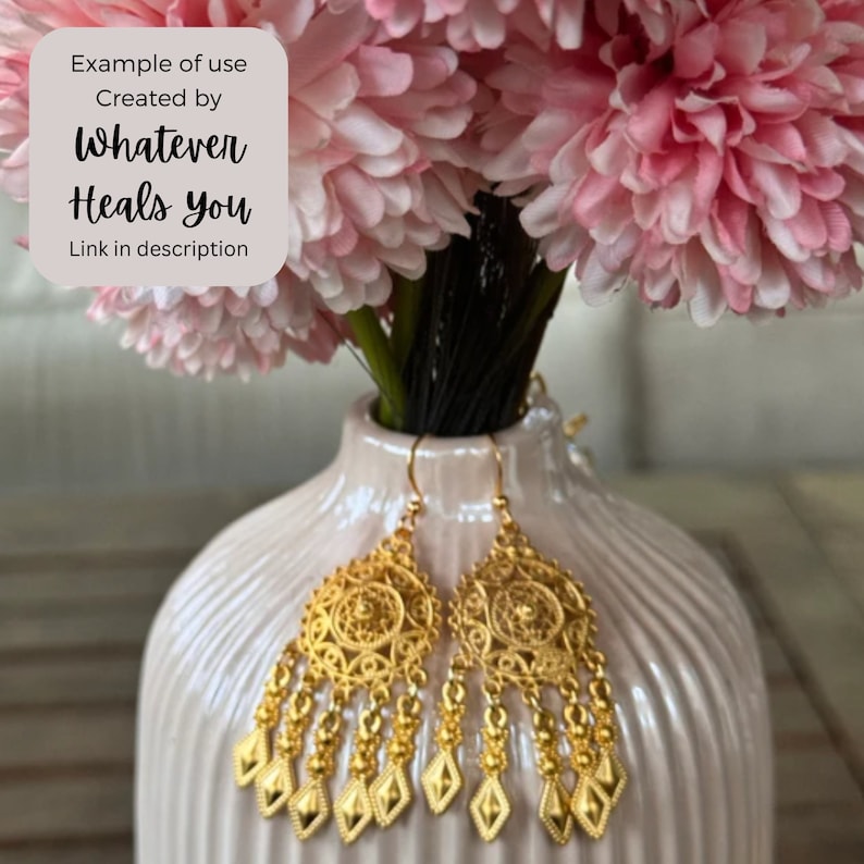 May include: A pair of gold dangle earrings with intricate filigree designs. The earrings feature a round, openwork top with a dangling chain of small, round beads and diamond-shaped charms.