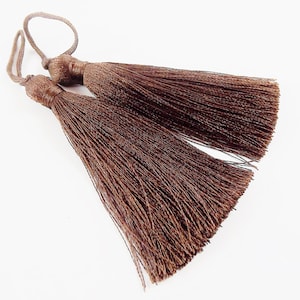Peut inclure: Deux glands marrons avec une boucle en haut. Les glands sont faits d'un matériau doux et soyeux et mesurent environ 7,5 cm de long.