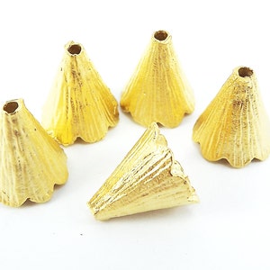 May include: Five gold-colored metal cone-shaped beads with scalloped edges. The beads are approximately 1 inch in diameter.