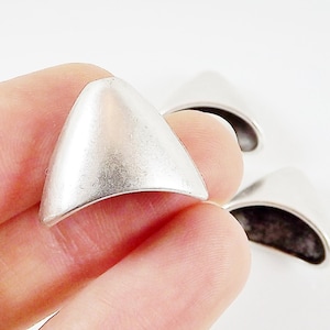 Puede incluir: Tapas de metal plateado para los extremos de los cordones. Las tapas tienen forma de triángulo con un borde redondeado.