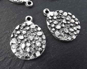 Peut inclure: Breloques en métal argenté avec une surface texturée et bosselée. Les breloques sont rondes et ont un trou en haut pour les attacher à des bijoux ou d'autres objets artisanaux.