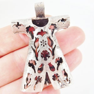 Pu&ograve; includere: Ciondolo color argento con un design floreale stilizzato. Il ciondolo ha una finitura strutturata e presenta forme floreali e di foglie ritagliate con accenti rossi e rosa. Il ciondolo &egrave; tenuto in mano su sfondo bianco.