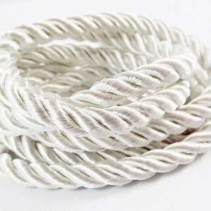 May include: White braided rope cord, a thick, twisted rope made of white fabric, ideal for crafting and home decor projects.