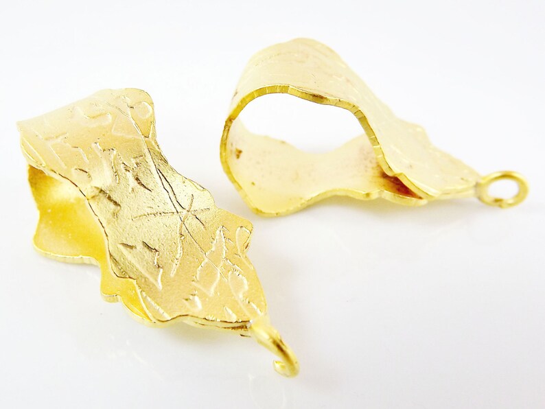 Puede incluir: Dos cierres de metal dorado con un dise&ntilde;o decorativo y texturado. Cada cierre tiene un bucle en un extremo y un gancho en el otro.