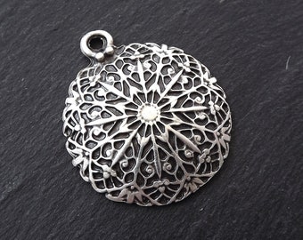 May include: Silver pendant with a detailed, intricate mandala design. The pendant has a loop at the top for attaching to a chain or cord.